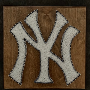 May include: White string art on a wooden background, forming the New York Yankees logo, "NY".