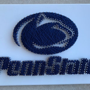 May include: A navy blue string art piece depicting the Penn State Nittany Lion logo and the word "Penn State" in a white background.