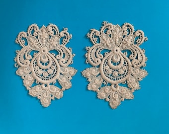 A pair of vintage lace applique motifs in cream.