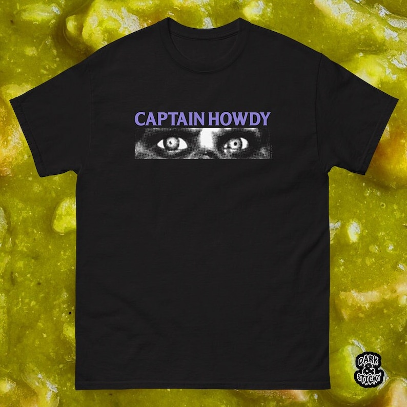 May include: Black t-shirt with a white graphic of a pair of eyes and the text "CAPTAIN HOWDY" in purple.