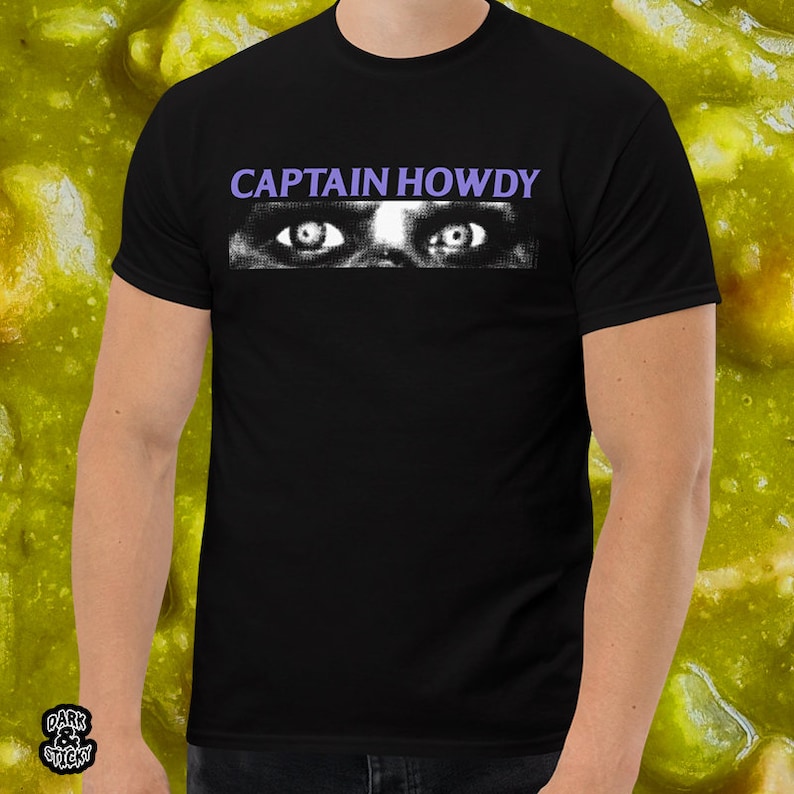 May include: Black t-shirt with the text "CAPTAIN HOWDY" in white letters and a graphic of two eyes with purple eyelids.