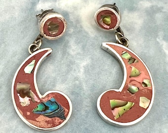May include: A pair of silver earrings with a crescent moon design. The earrings have a red-orange inlay with iridescent abalone shell accents. The earrings have a post-back closure.