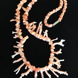 Op de afbeelding: Een roze koraal ketting gemaakt van kleine, vertakte stukjes koraal. De ketting is geregen op een zilveren ketting en heeft een zilveren sluiting.