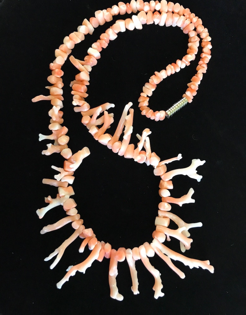 Op de afbeelding: Een roze koraal ketting gemaakt van kleine, vertakte stukjes koraal. De ketting is geregen op een zilveren ketting en heeft een zilveren sluiting.