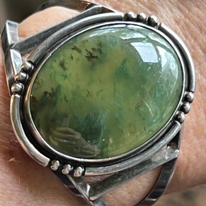 May include: A silver ring featuring a green agate stone set in a bezel setting. The stone displays a mottled green and brown pattern.