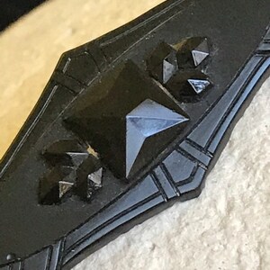 May include: A black jet brooch with a geometric design and black glass stones.