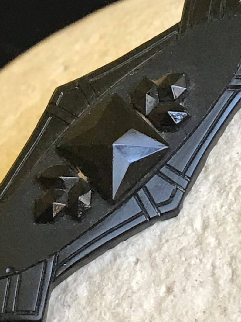 May include: A black jet brooch with a geometric design and black glass stones.