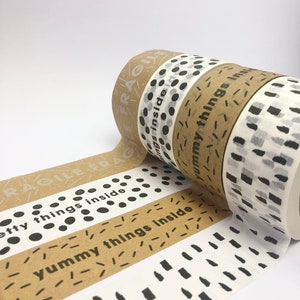 May include: Four rolls of brown paper tape with different black and white patterns. The tape has the text "fragile" and "yummy things inside" printed on it.