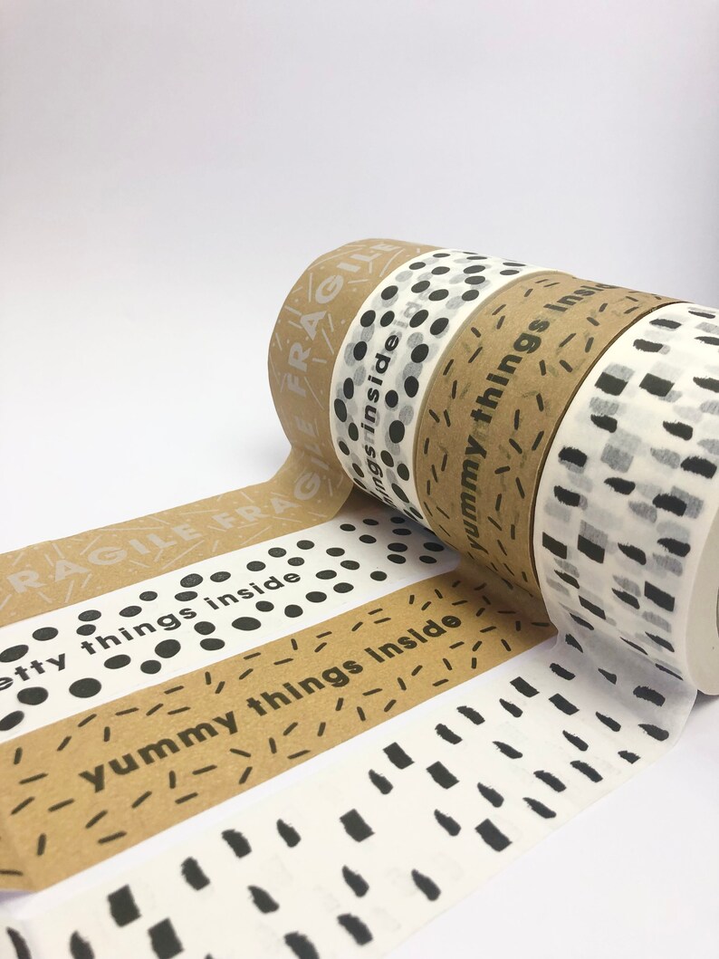 May include: Four rolls of brown paper tape with different black and white patterns. The tape has the text "fragile" and "yummy things inside" printed on it.