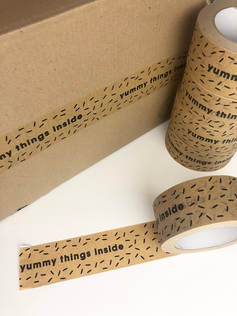 May include: Brown paper tape with a repeating pattern of black dashes and the text "yummy things inside" printed in black.