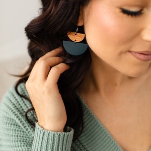 May include: A pair of dangle earrings with a dark green and brown wood design. The earrings are made of two half circles, one on top of the other.