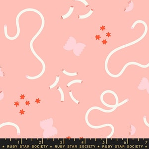 May include: A pink fabric with a repeating pattern of white noodle shapes, pink bow tie pasta, and small red starbursts. The fabric has a ruler along the bottom with the text "RUBY STAR SOCIETY".
