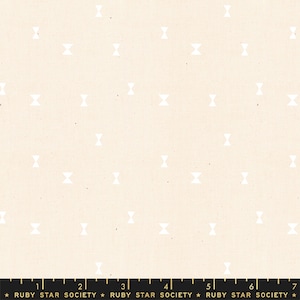 May include: Cream-colored fabric with a repeating pattern of white bow tie shapes. The fabric has a subtle texture and a ruler along the bottom with the text "RUBY STAR SOCIETY".