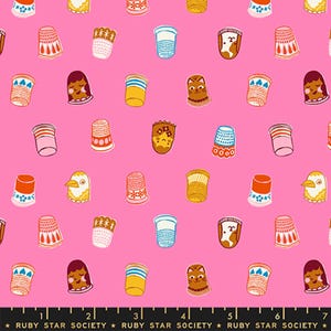 May include: A bright pink fabric featuring a repeating pattern of various thimbles, including designs with faces, animals, and geometric motifs. A black ruler edge at the bottom displays the text Ruby Star Society.