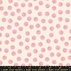 May include: Fabric with a repeating pattern of pink smiley faces on a cream background. The faces have orange smiles and are evenly spaced across the fabric. The bottom of the image has text that reads "RUBY STAR SOCIETY".