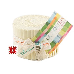 May include: A roll of cream-colored fabric strips, tied with a cream ribbon and a colorful tag. The ribbon is tied in a bow and has the word "moda" embroidered on it in red and teal. The tag reads "BELLA SOLIDS moda".