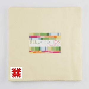 May include: A square, pale yellow fabric with a serged edge. A rectangular label with the text "BELLA SOLIDS moda" is centered on the fabric. The label has a colorful, geometric design. A red and white logo is in the lower left corner.