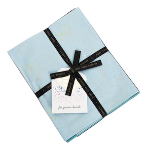 May include: A bundle of fabric fat quarters tied with a black ribbon. The fabric is light blue with yellow and white speckles. A white tag with the text "fat quarter bundle" is attached to the ribbon. The ribbon is printed with "RUBY STAR SOCIETY".