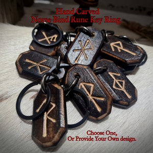 May include: A set of hand-carved wooden keychains featuring Norse bind runes. Each keychain is attached to a black metal ring. The keychains are arranged on a light wood surface. "Choose One, Or Provide Your Own design." is written in red text at the bottom of the image.