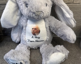May include: A gray plush bunny with long ears and a white belly patch. The patch features a photo and the text "A Hug From Heaven." The bunny's foot is embroidered with the word "Grandad."