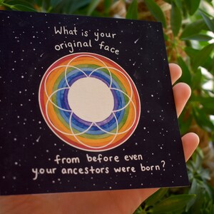 Puede incluir: Una tarjeta negra con un c&iacute;rculo arco&iacute;ris y estrellas blancas. El texto en la tarjeta dice "&iquest;Cu&aacute;l es tu rostro original de antes incluso de que tus ancestros nacieran?"
