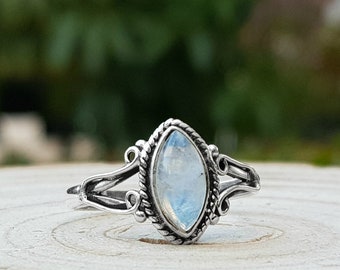May include: A silver ring featuring a marquise-shaped moonstone set in a delicate filigree design.