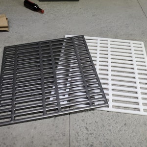 May include: Two square metal grilles, one black and one white, with a grid pattern of rectangular bars.
