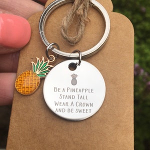 May include: A silver keyring with a pineapple charm and a round silver tag that says "Be a Pineapple Stand Tall Wear a Crown And Be Sweet".