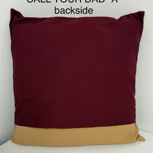 May include: A burgundy pillow with a gold trim. The back of the pillow has the text "CALL YOUR DAD "A"" printed on it.