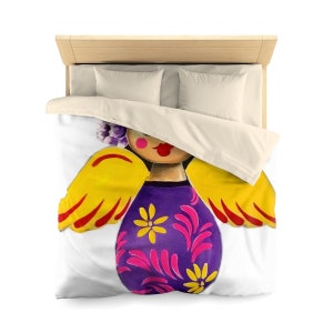 May include: A white duvet cover with a colorful angel illustration. The angel has yellow wings, a purple dress with pink and yellow flowers, and a pink face with red lips.