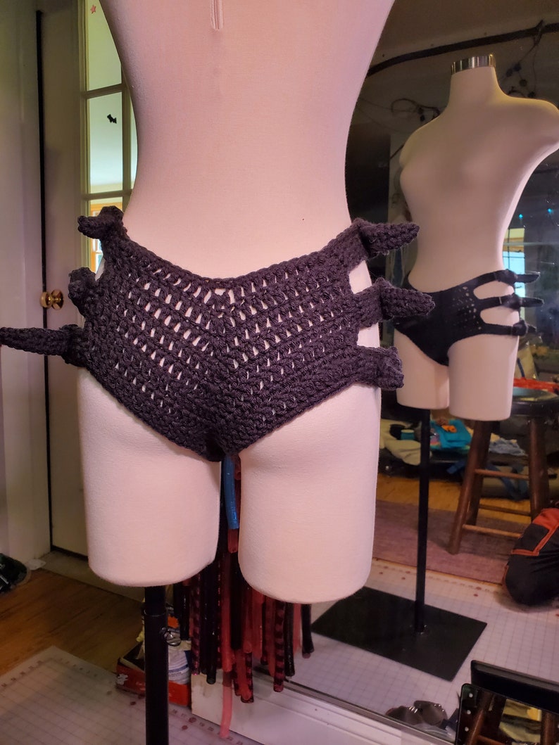 May include: Black crocheted underwear with a unique design featuring cutouts and a high-waisted fit.