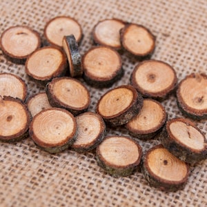 Pode incluir: Uma coleção de fatias de madeira natural, cada uma com um padrão de grão único, dispostas sobre um fundo de juta. As fatias são de vários tamanhos e formas, com uma estética rústica e orgânica.