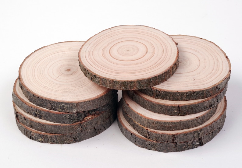 May include: A stack of eight round wooden slices, each with a natural bark edge and a light brown color. The wood grain is visible on each slice, showing the rings of the tree.