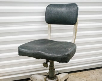 May include: A vintage office chair with a black vinyl seat and backrest, a white star-shaped base, and five black wheels.