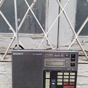 May include: A gray Sony ICF-7600DS radio with a telescoping antenna. The radio has a digital display, buttons for tuning, and preset options. The text "SONY" is visible on the front.
