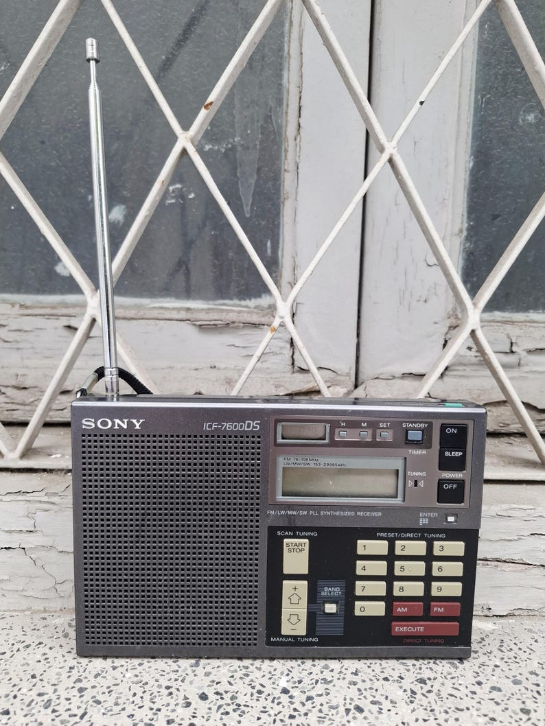 May include: A gray Sony ICF-7600DS radio with a telescoping antenna. The radio has a digital display, buttons for tuning, and preset options. The text "SONY" is visible on the front.