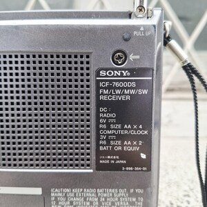 May include: A silver Sony ICF-7600DS FM/LW/MW/SW receiver radio. The radio has a pull-up antenna and a black label with text including "MADE IN JAPAN". The radio requires 4 AA batteries or equivalent.