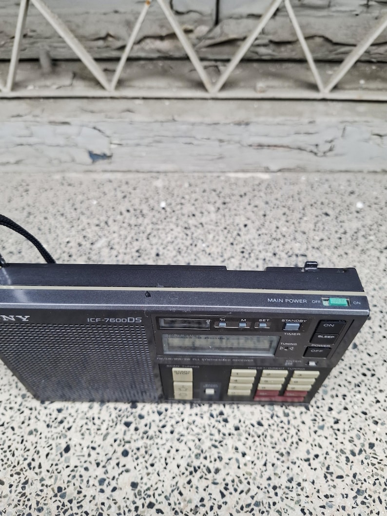 May include: A black Sony ICF-7600DS portable radio with a mesh speaker cover and a digital display. The radio has several buttons and a tuning dial. The main power switch is set to off.