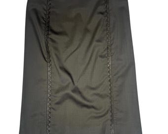 May include: A dark olive-green skirt with vertical decorative stitching down the front. The skirt has a tailored fit and a subtle sheen, suggesting a formal or professional style. The skirt is a knee-length design.