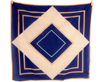 May include: A blue and orange patterned silk scarf with a geometric design. The scarf is hanging from two clothes pegs.