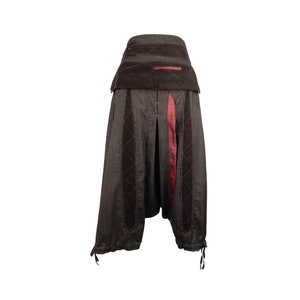 Op de afbeelding: Bruine en zwarte gepatroneerde broek met een rode streep in het midden. De broek heeft een brede tailleband en een losse pasvorm.