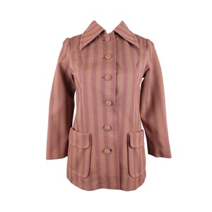 Puede incluir: Una chaqueta de rayas de color malva con cierre de botones y dos bolsillos. La chaqueta tiene un cuello ligeramente acampanado.