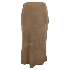 May include: A brown suede skirt with a unique design featuring multiple panels and seams. The skirt has a straight silhouette and falls to the mid-calf.