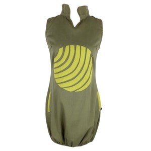 Puede incluir: Un vestido verde sin mangas con un diseño circular amarillo. El círculo tiene un patrón de rayas.