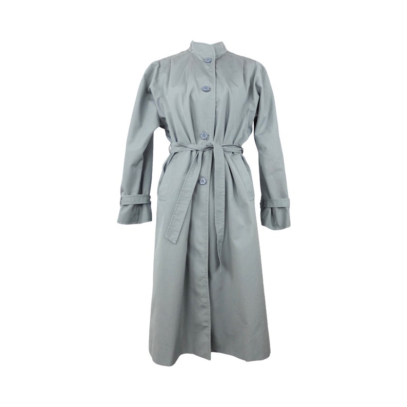 May include: A long, light gray trench coat with a button-up front and a matching belt. The coat has a stand-up collar and long sleeves.