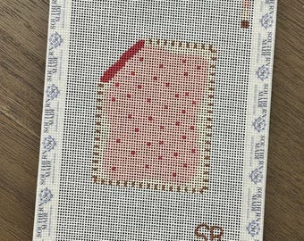 May include: Needlepoint canvas with a rectangular design featuring a red and pink pattern. The canvas has a white border with the text "SOUTHERN MADE" repeated around the edges. The initials "SR" are visible.