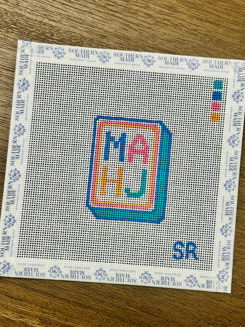 May include: Needlepoint canvas with the letters "MA HJ" in a colorful, blocky design. The letters are outlined in a bright pink, with a teal border. The canvas has a white background with the text "SOUTHERN MADE" around the edges.