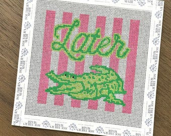 May include: Needlepoint canvas with a pink and white striped background. The word "Later" is stitched in green cursive above a green alligator. The canvas is bordered with the words "Southern Made".