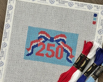 May include: A square needlepoint canvas featuring a light blue rectangular center with a red, white, and blue bow graphic above the number 250 in red. The border is printed with the text Southern Made. Four skeins of embroidery floss in red, white, dark blue, and light blue are included.