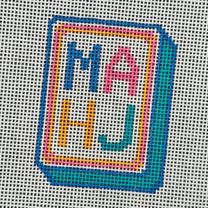May include: Needlepoint canvas with the letters "MA HJ" in blue, pink, and yellow, framed in a teal border. The letters are stitched on a white background, creating a colorful, geometric design. The canvas is likely for a craft project.